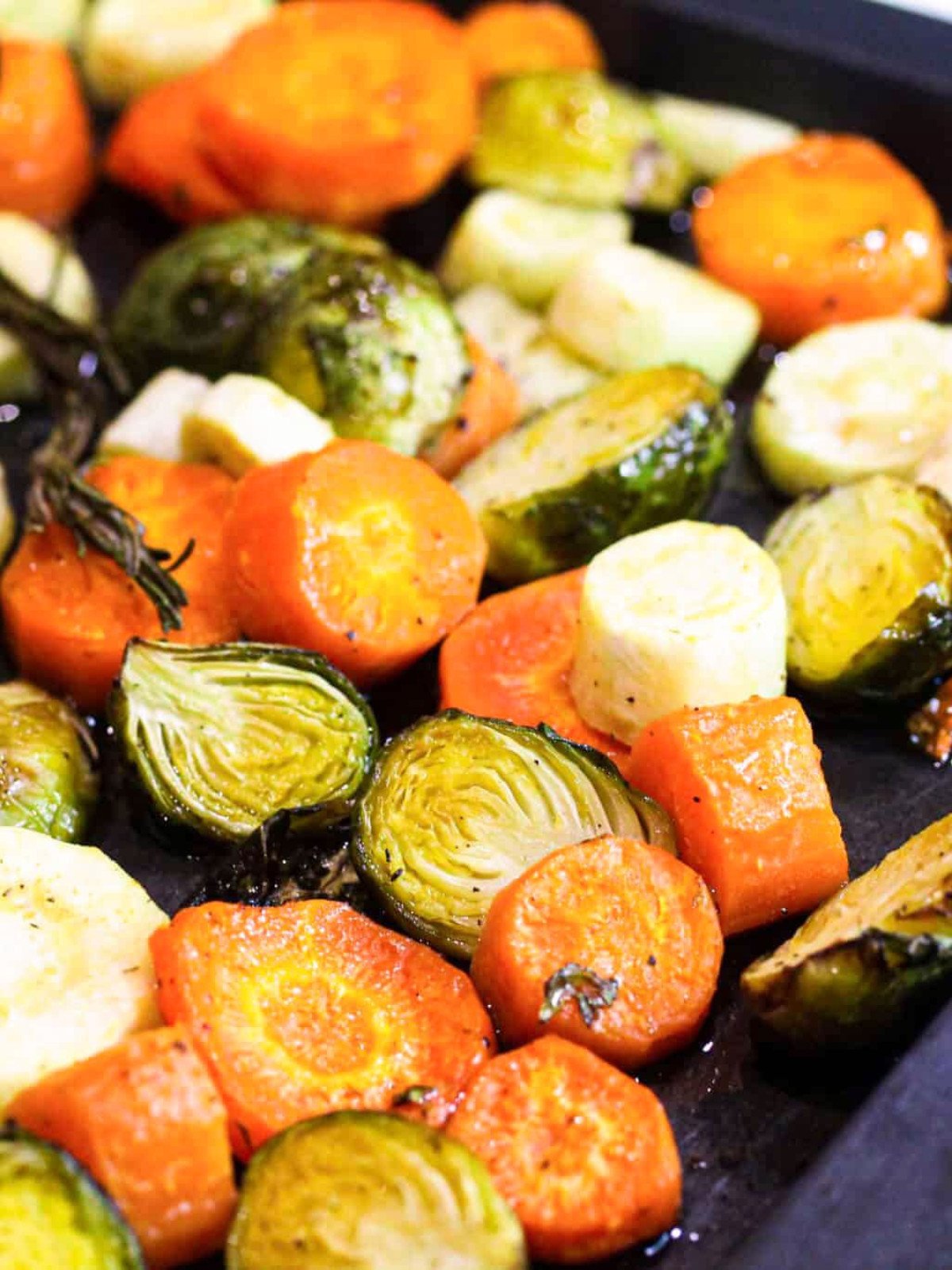 Carrots, brussels and parsnips on a baking tray.