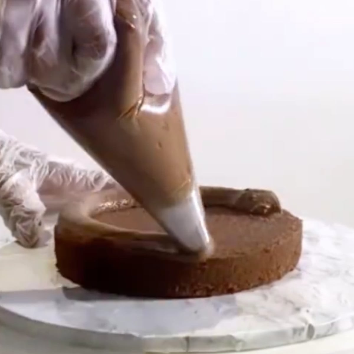 Chocolate cake with a layer of chocolate ganache on a cake board.