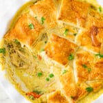 Creamy turkey and vegetable pie topped with herbs in a white circular dish.