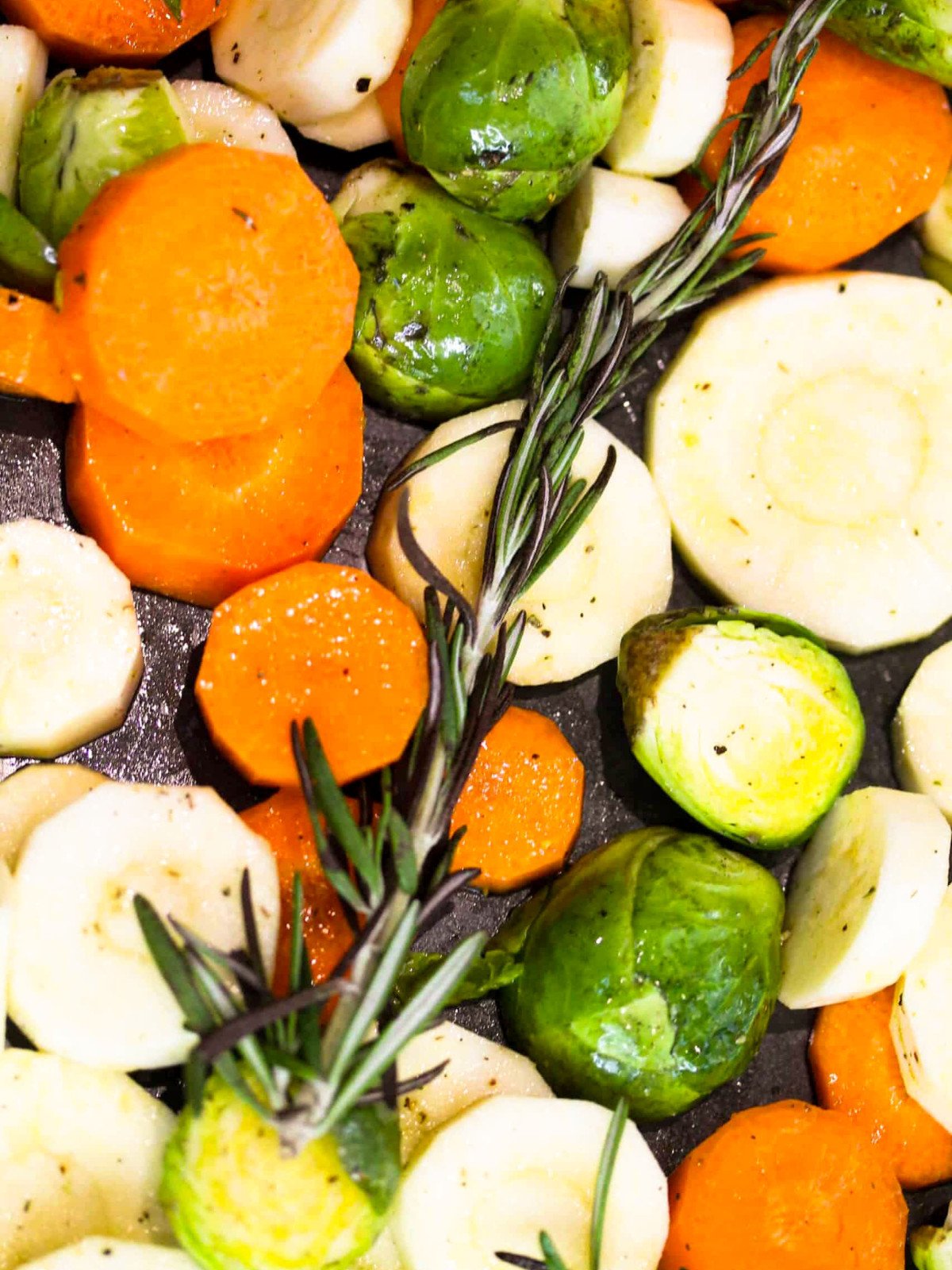 Raw carrots, brussels and parsnips on a baking tray.