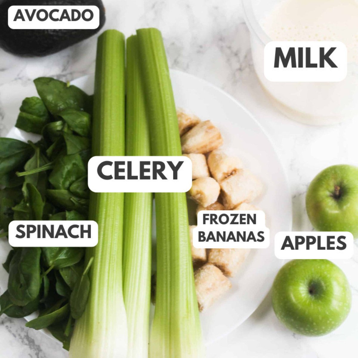 Avocado, celery, spinach, frozen banans, milk and apples on a table.