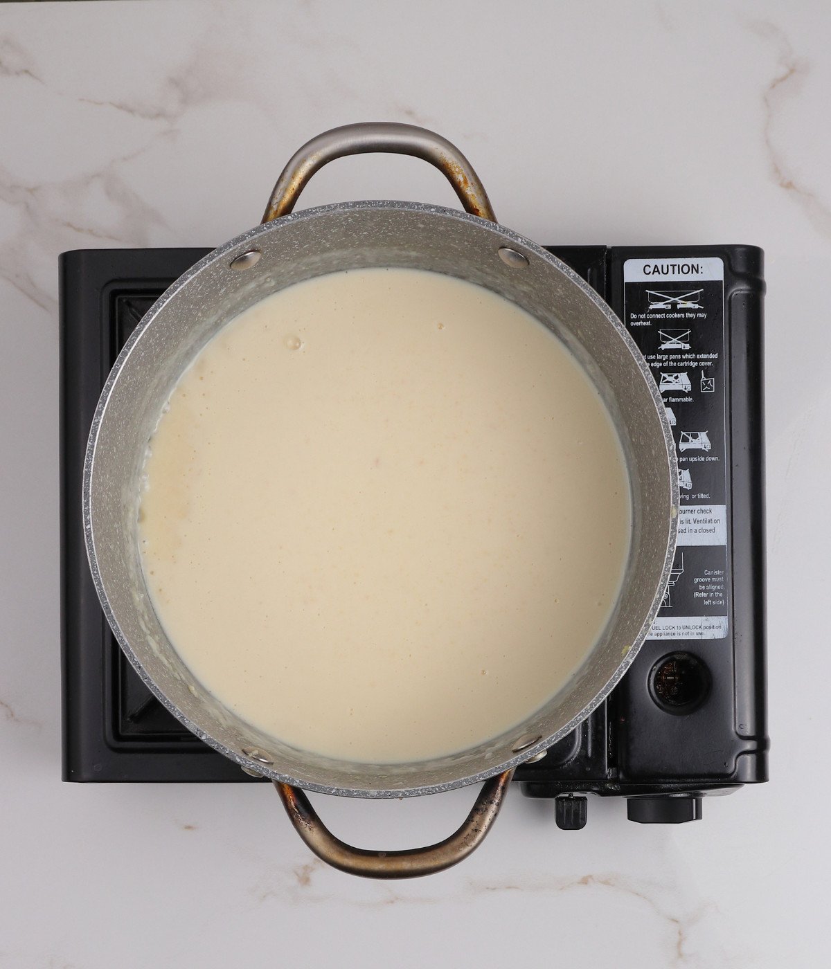 Butter, flour, milk and double cream mixed in a large grey pot.