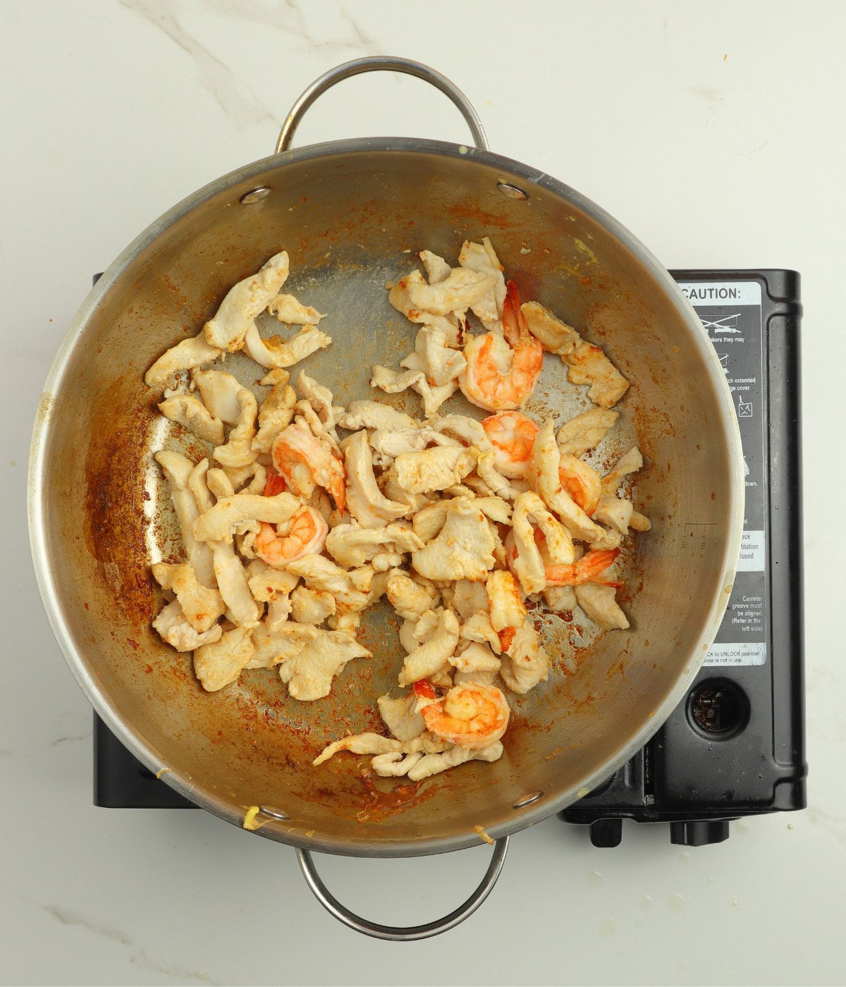 Chicken and shrimp cooked in a silver wok.
