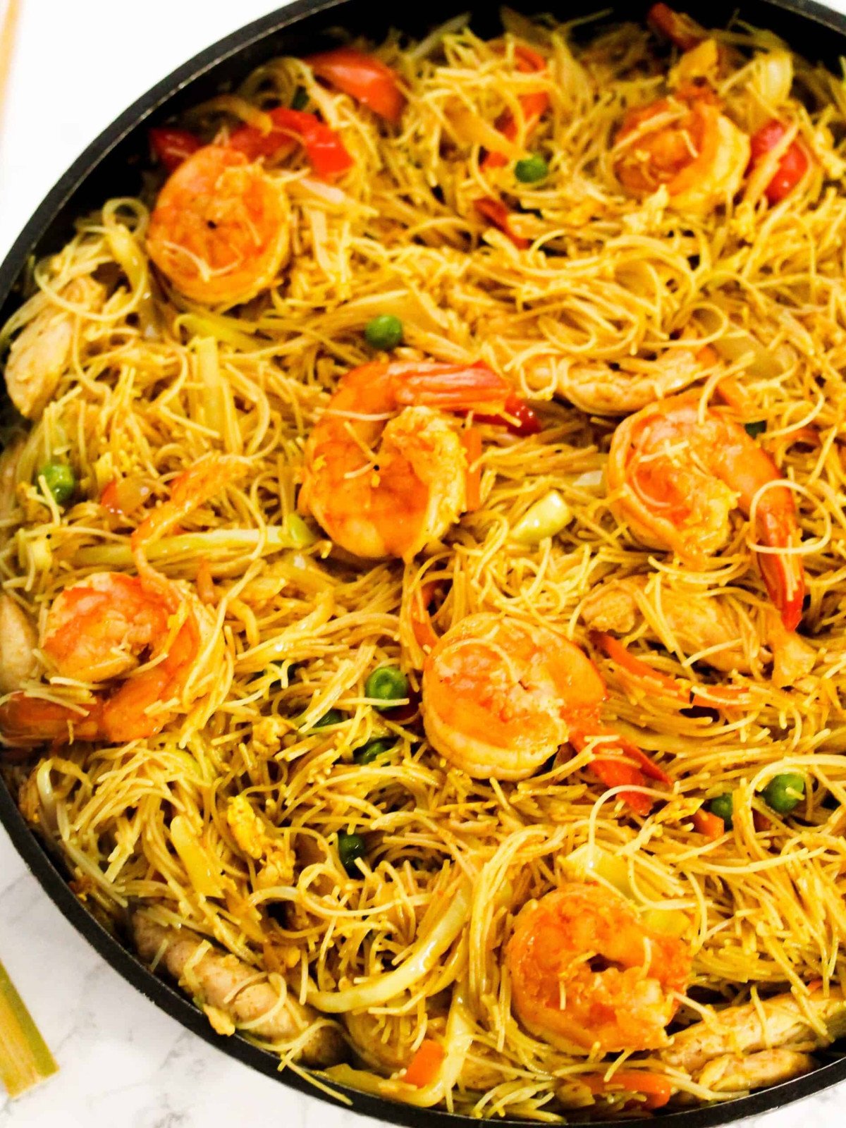 Singapore vermecelli with shrimp, chicken, eggs, peas and veggies in pan.