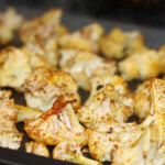 Spicy cauli florets on a grey tray.