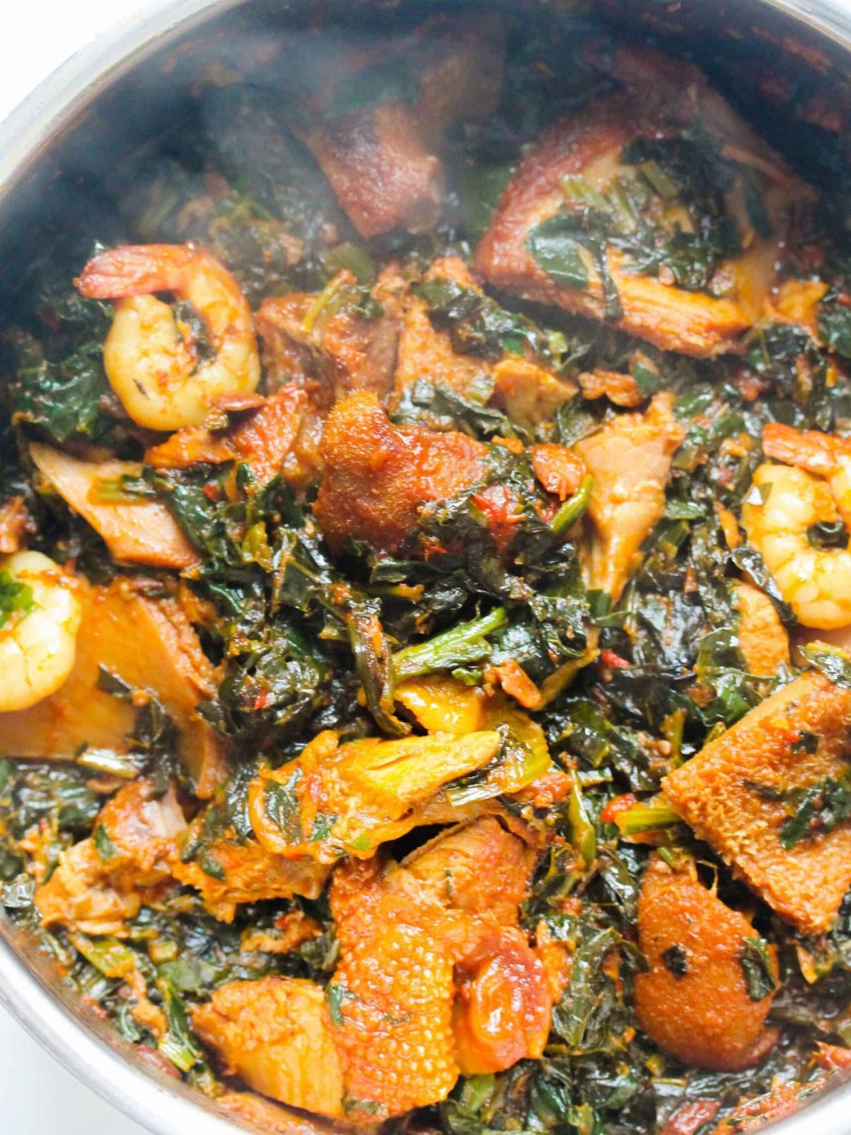 Stewed spinach with shrimp, chicken and tripe in a silver pot.