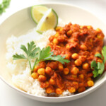 Tomato chickpeas sauce, rice, lime and herbs in a bowl.