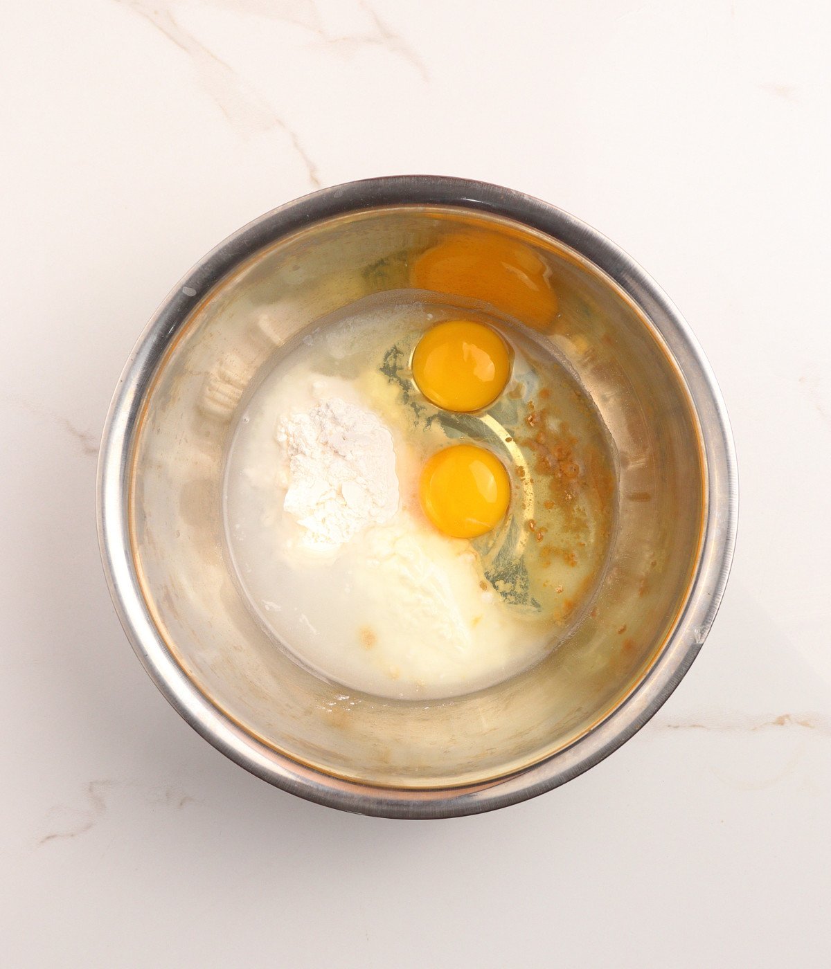 Eggs, cornflour, water and seasoning in a silver bowl.