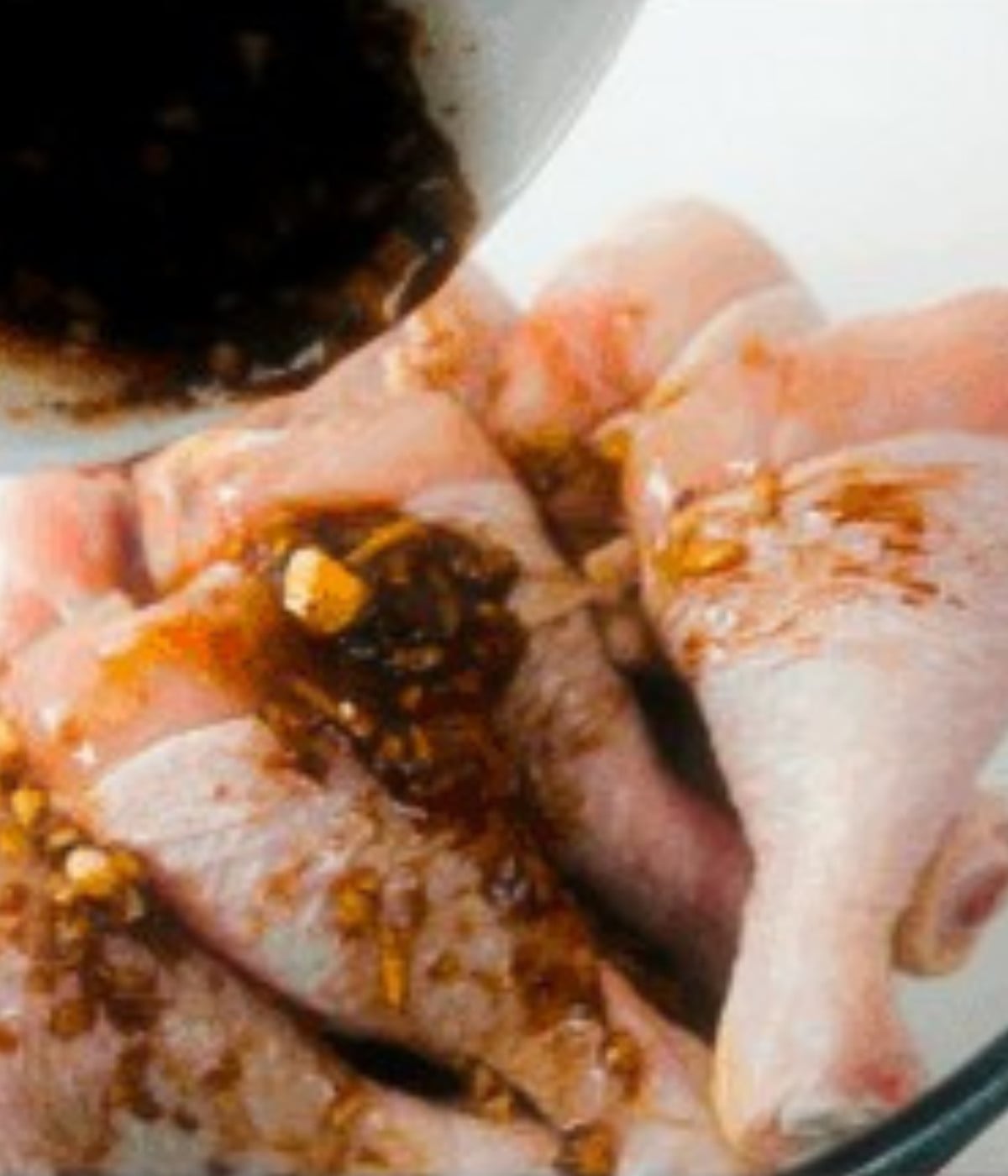 Honey soy marinade poured into uncooked chicken drums.
