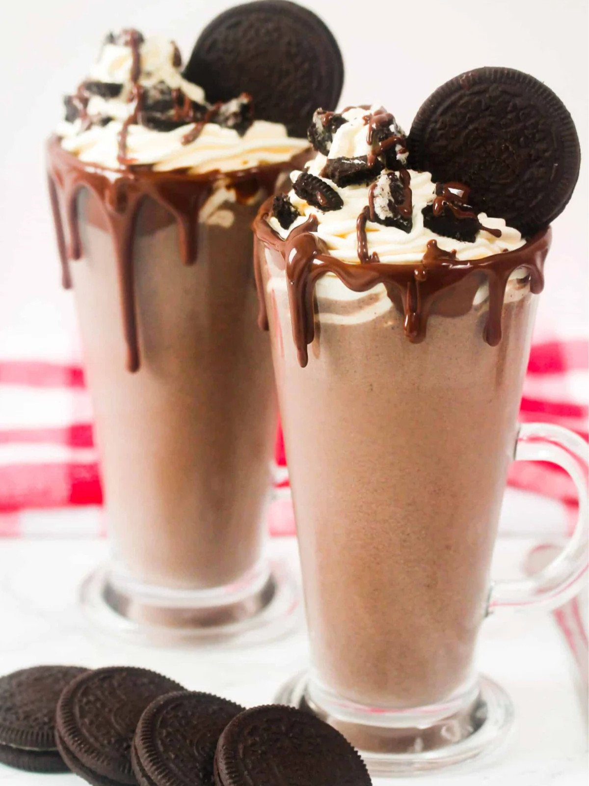 Oreo milkshake topped with whipped cream and chocolate sauce in a tall dessert cup.