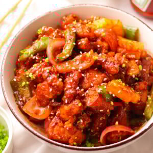Sweet and sour chicken in a bowl garnished with sesame seeds.