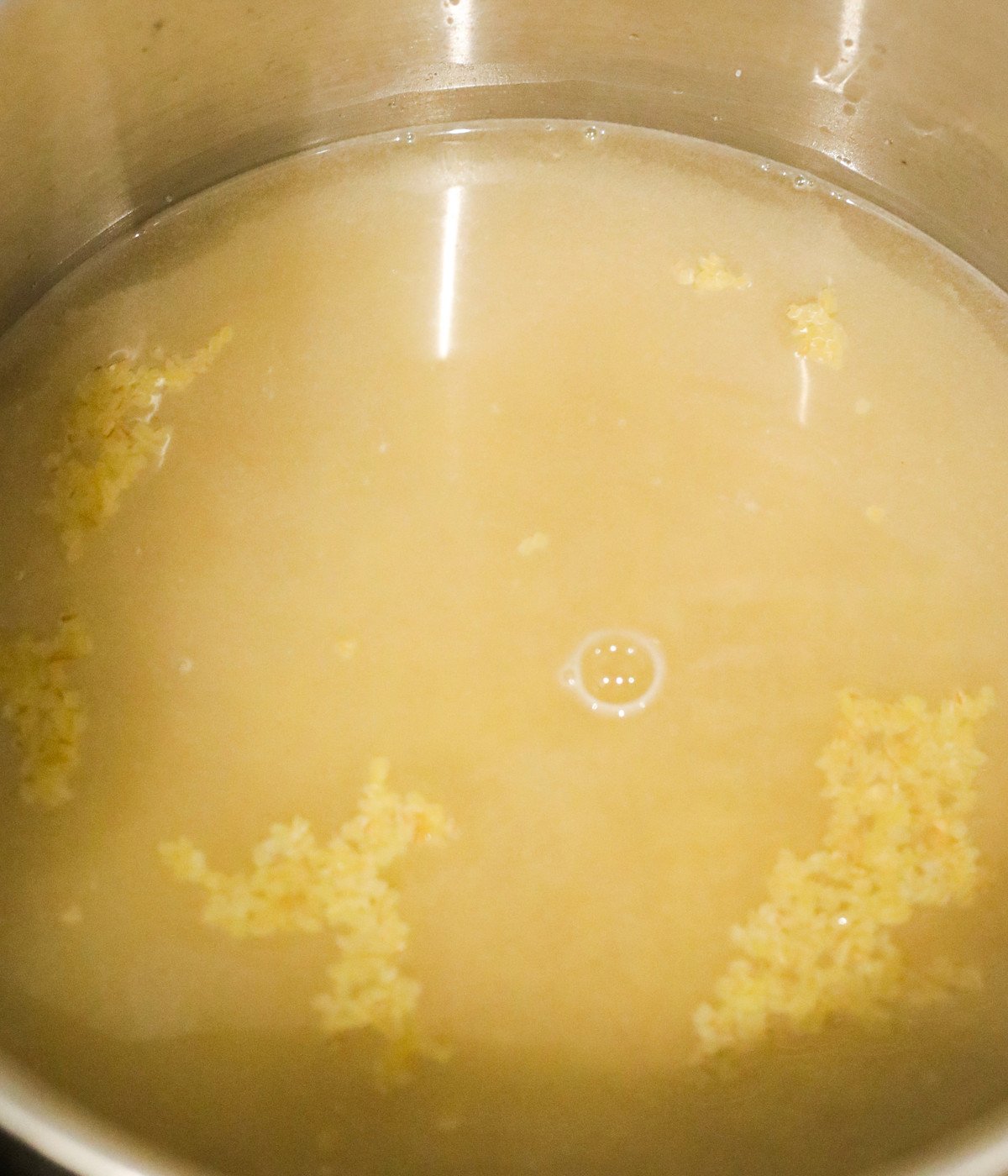 Bulgur wheat and water cookin in a silver pot.