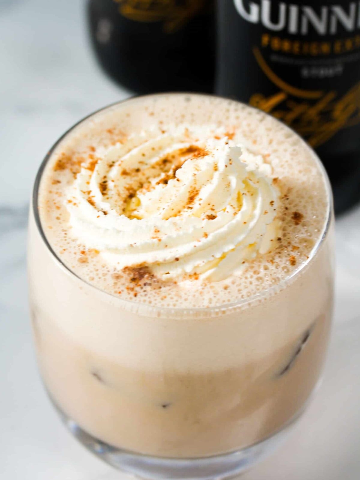 Guinness punch in a glass cup with whipped cream and nutmeg.