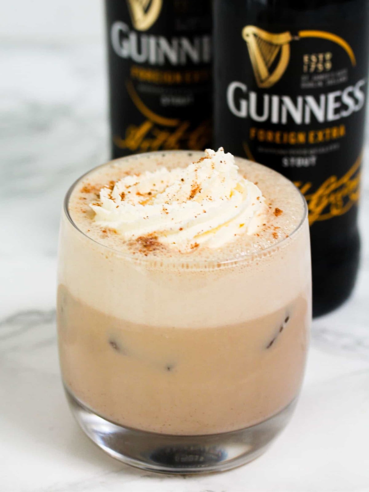 Guinness punch topped with whipped cream and nutmeg in a glass cup.