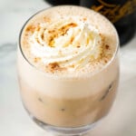 Stout punch in a glass cup topped with whipped cream.