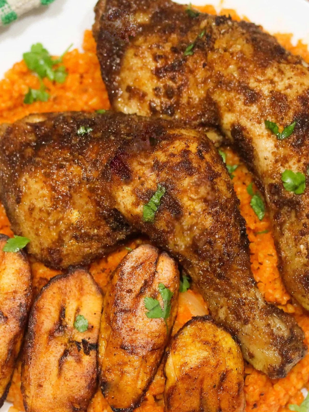 Suya chicken leg serve with Jollof rice and plantain topped with fresh parsley.
