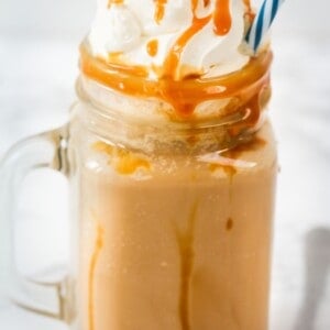 caramel Frappuccino with whipped cream and caramel sauce in a jar with a blue straw