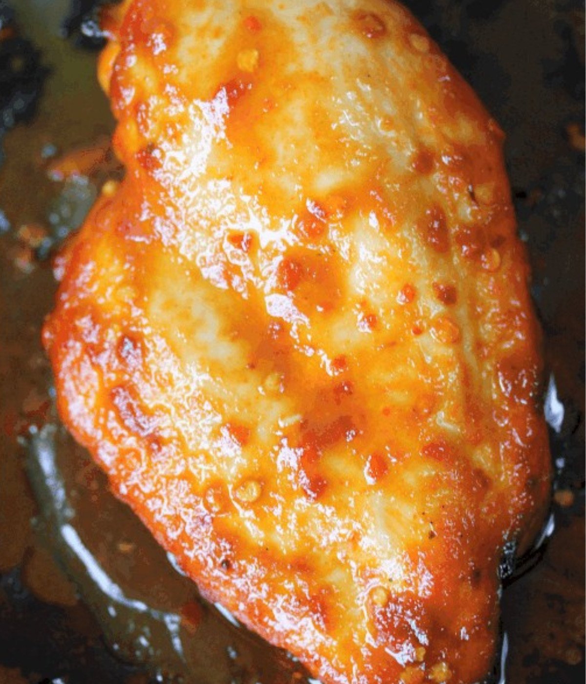 Chicken breast with siraccha on a baking tray.