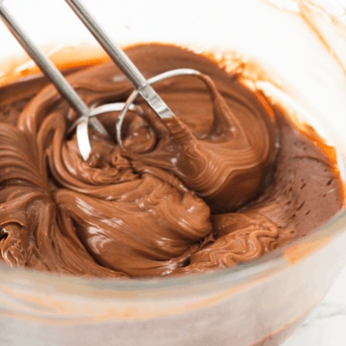 Hardened milk chocolate whisked in a glass bowl.