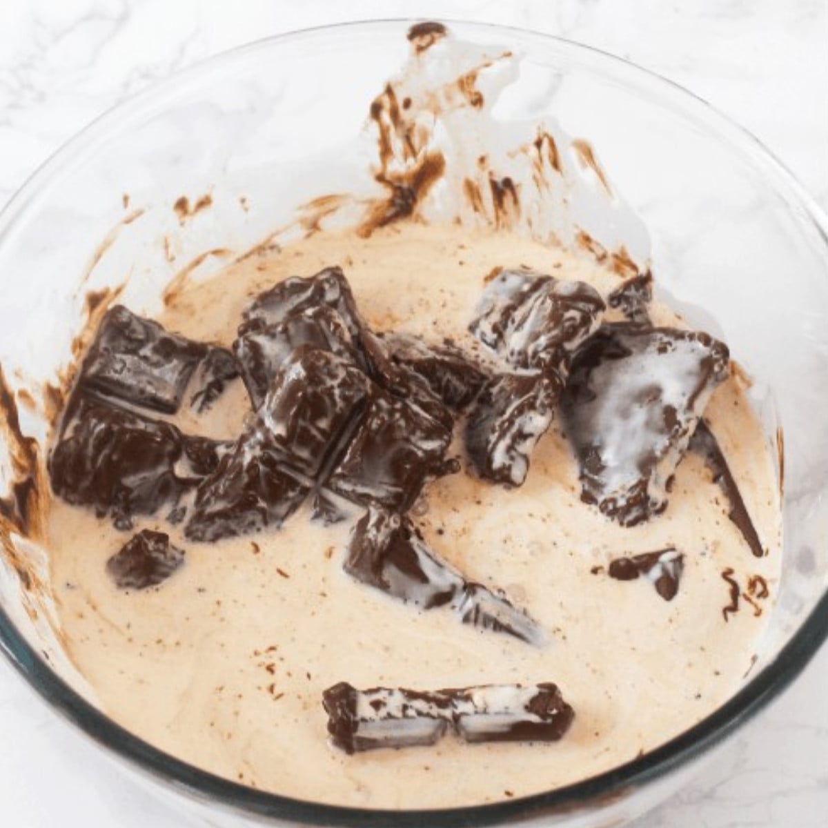 Milk chocolate and heavy cream in a glass bowl.