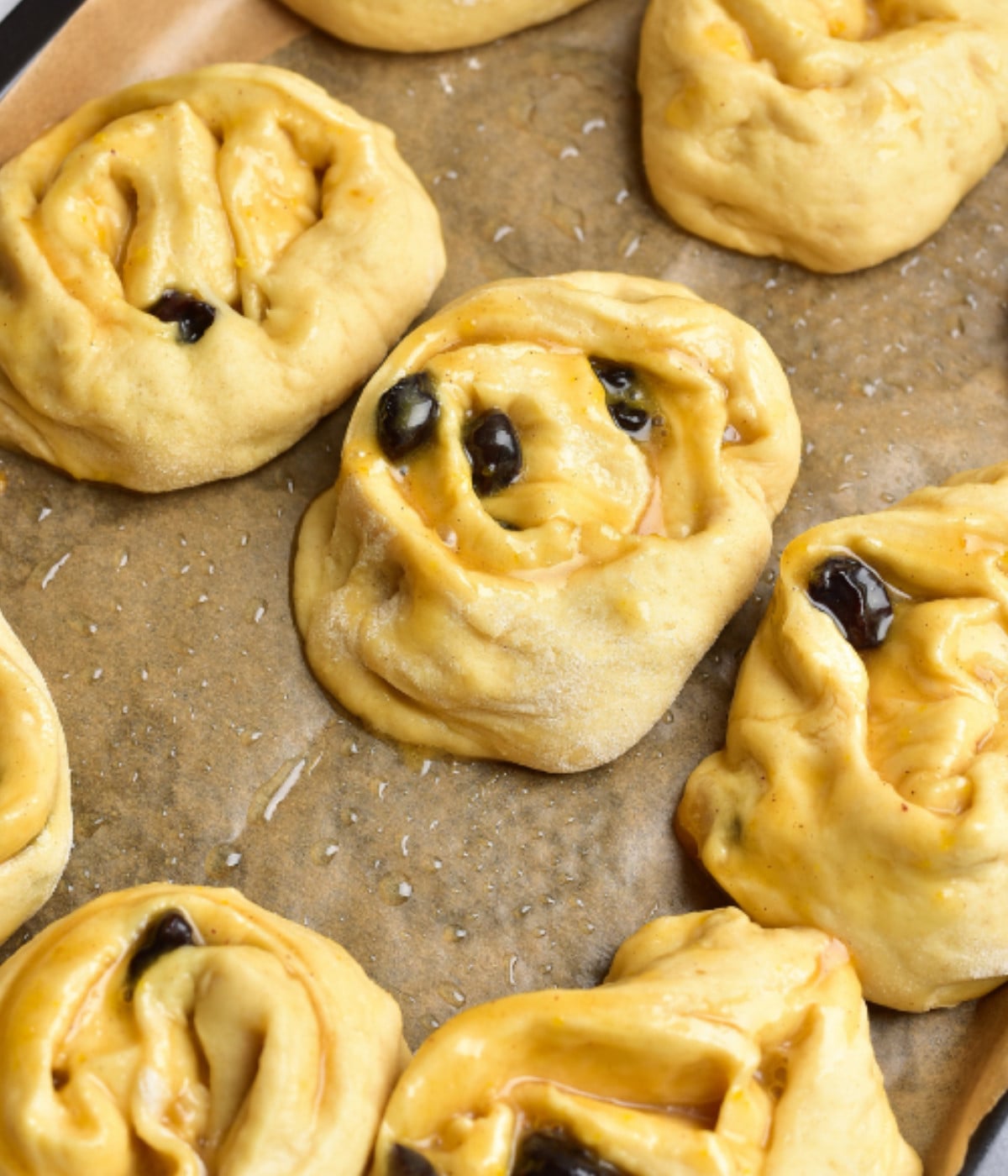 Evenly sliced rolled dough filled with fruit curd on a lined baking tray.