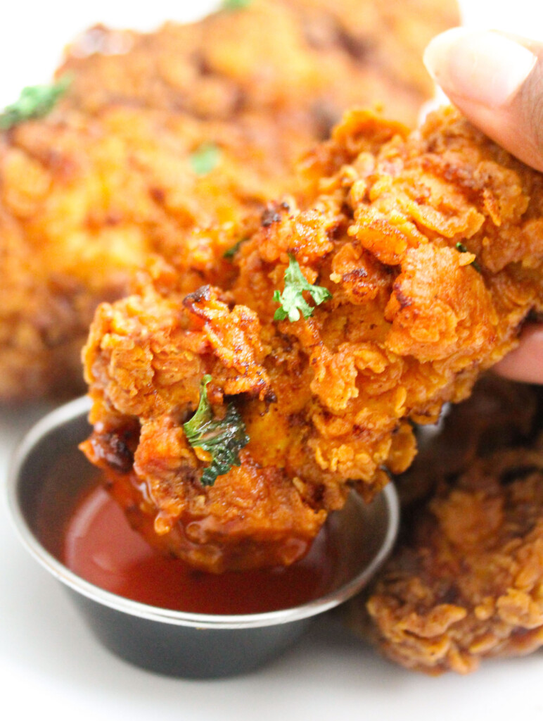 Dipping crispy chicken tenders into hot sauce