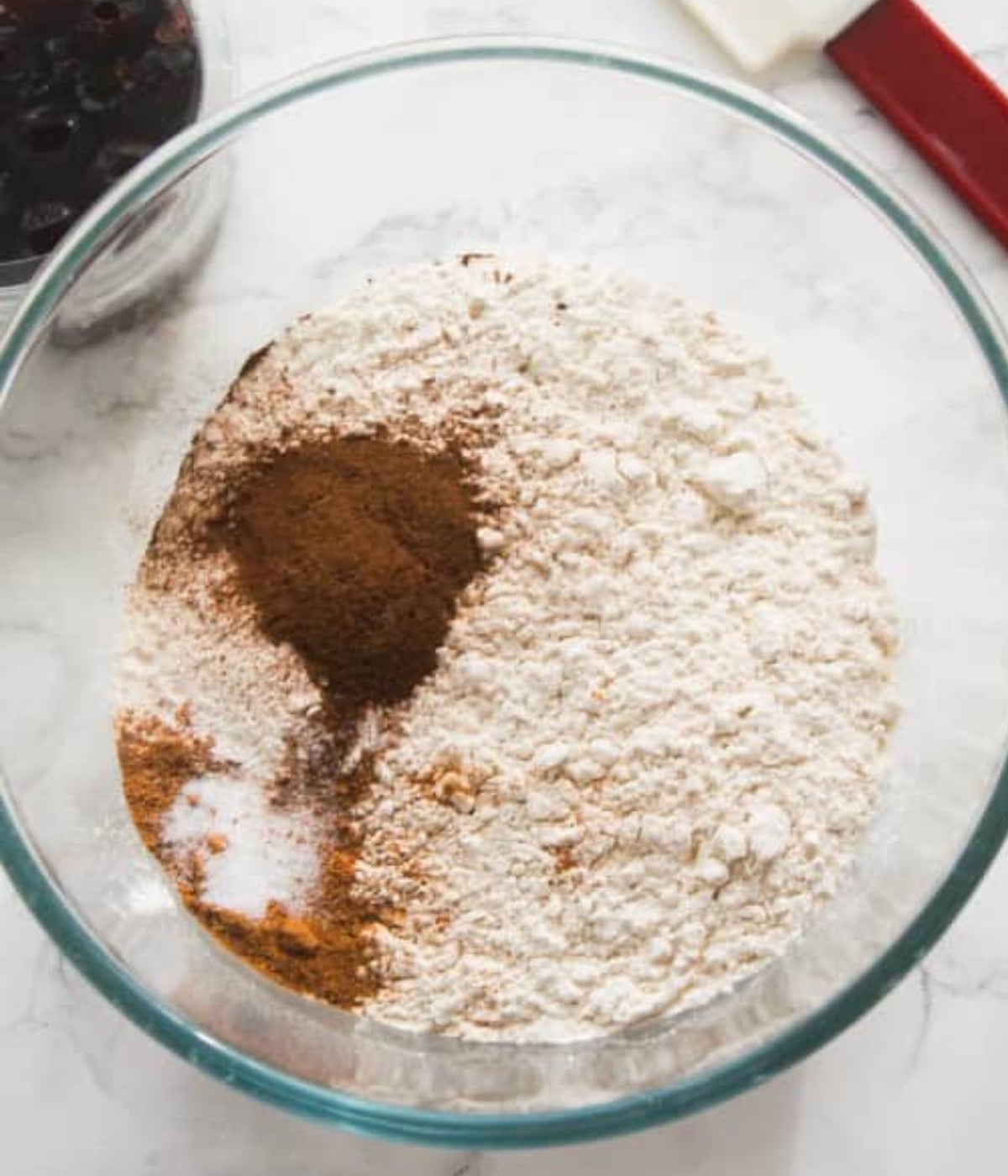 Flour, baking powder, cinnamon, nutmeg and salt in a glass bowl.