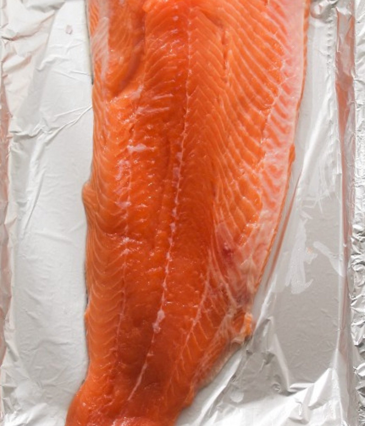 Raw salmon fillet on a baking tray lined with foil.