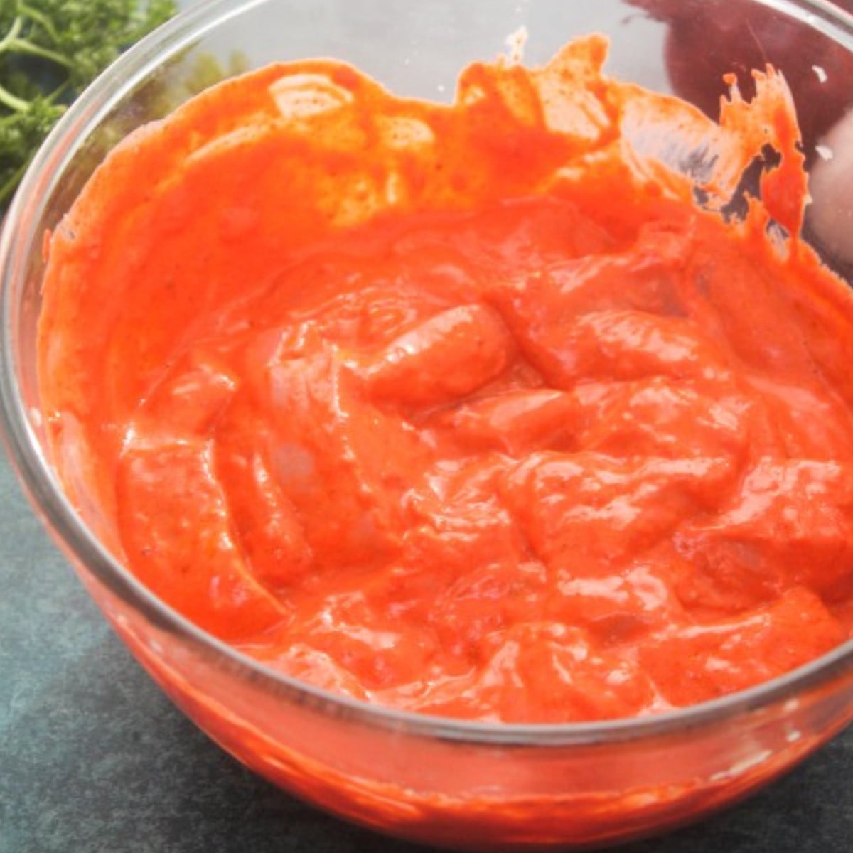 Tandoori marinade and chicken mixed in a glass bowl.