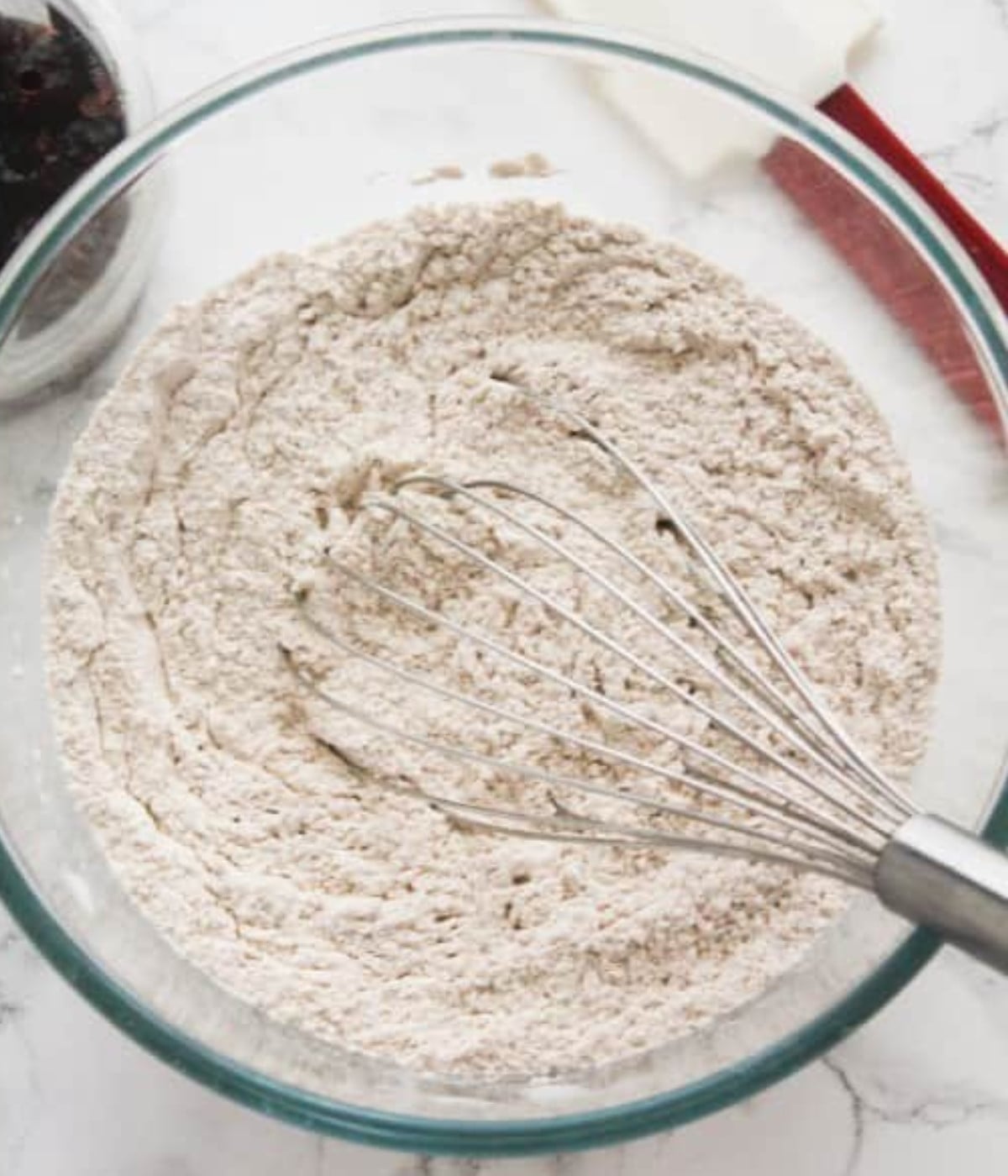 Whisked flour, baking powder, cinnamon, nutmeg and salt in a glass bowl.