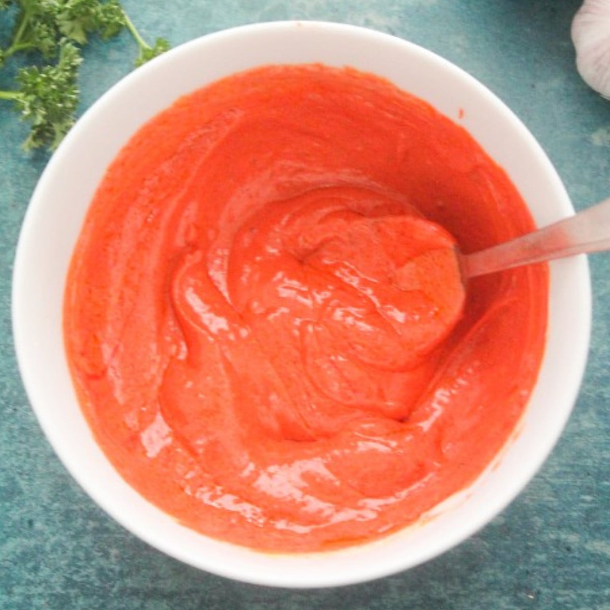 Yogurt, tumeric, cayenne pepper and tandoori mixed in a white bowl.