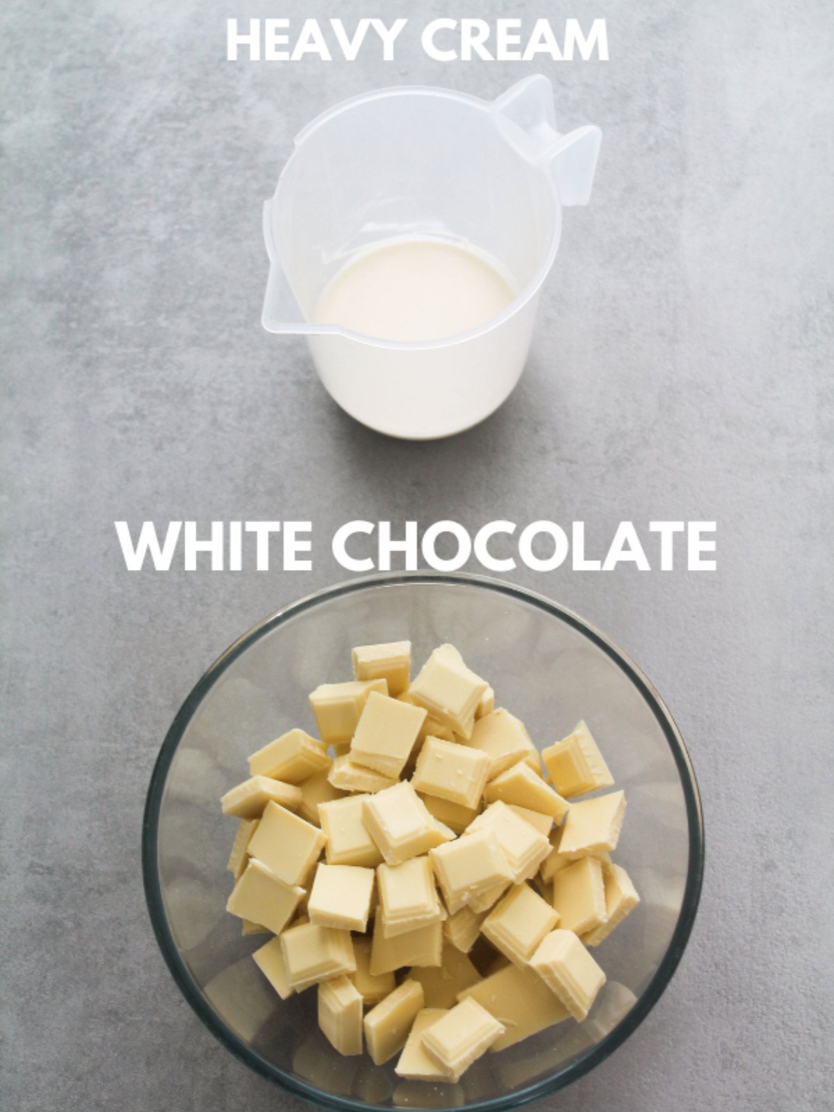 Heavy cream and white chocolate in a glass bowl on a grey backdrop.