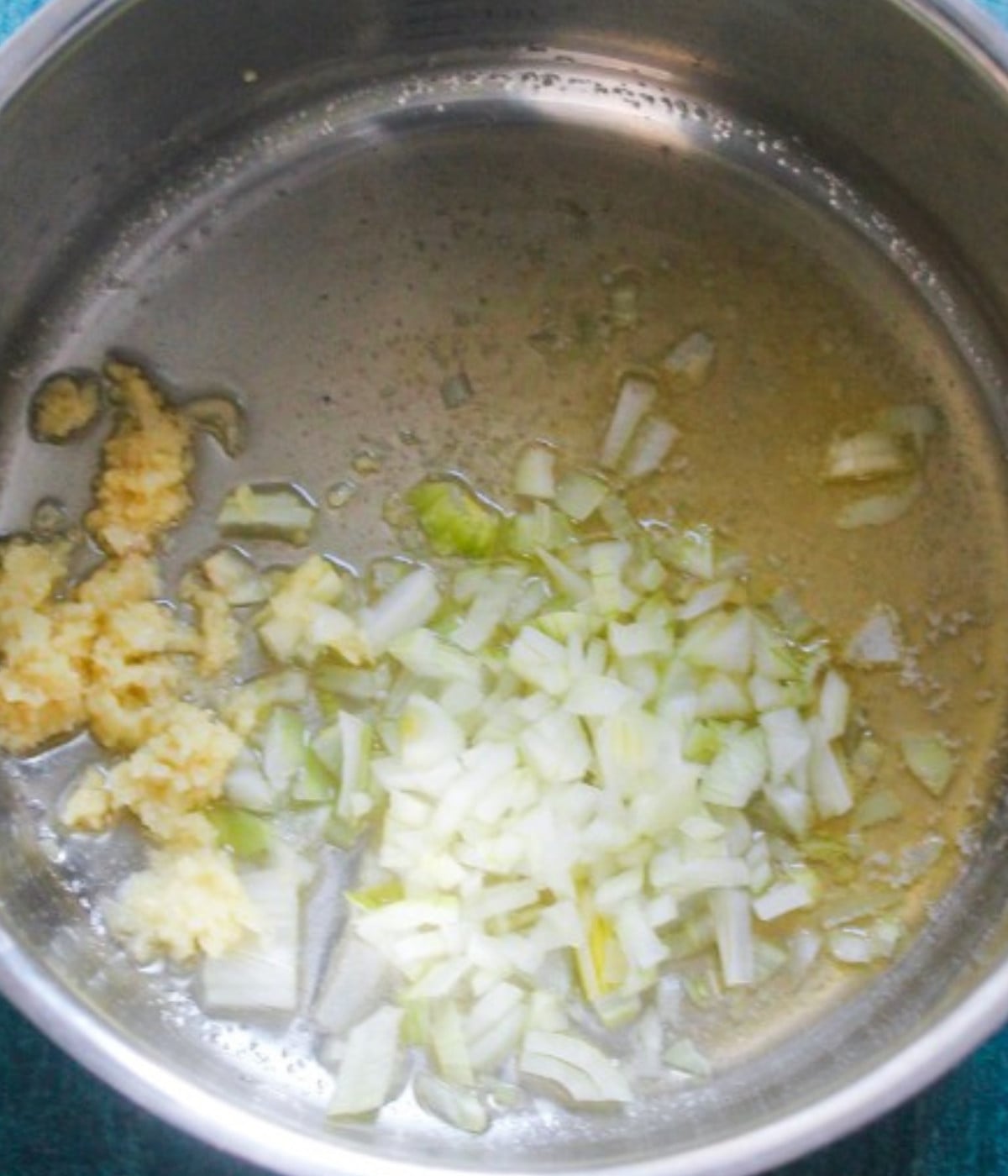 Butter melted, garlic, and chopped onions in a silver pot.