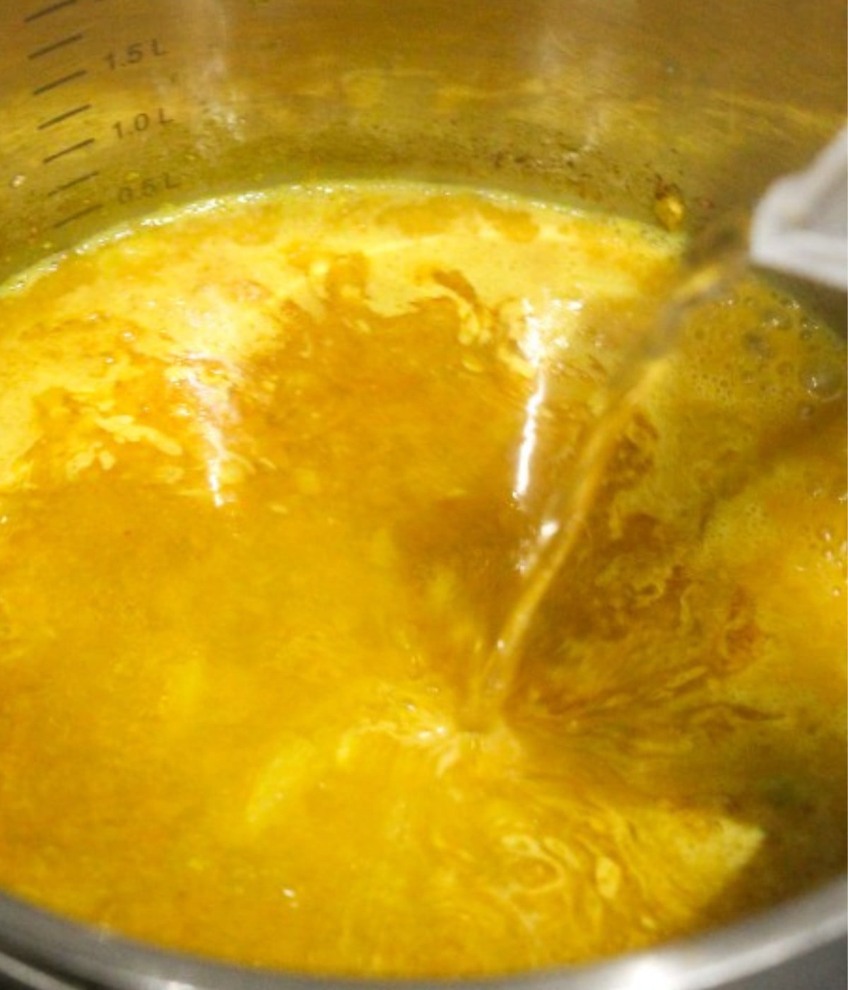 Mixed butter melted, garlic, turmeric, chopped onions and water in a silver pot.