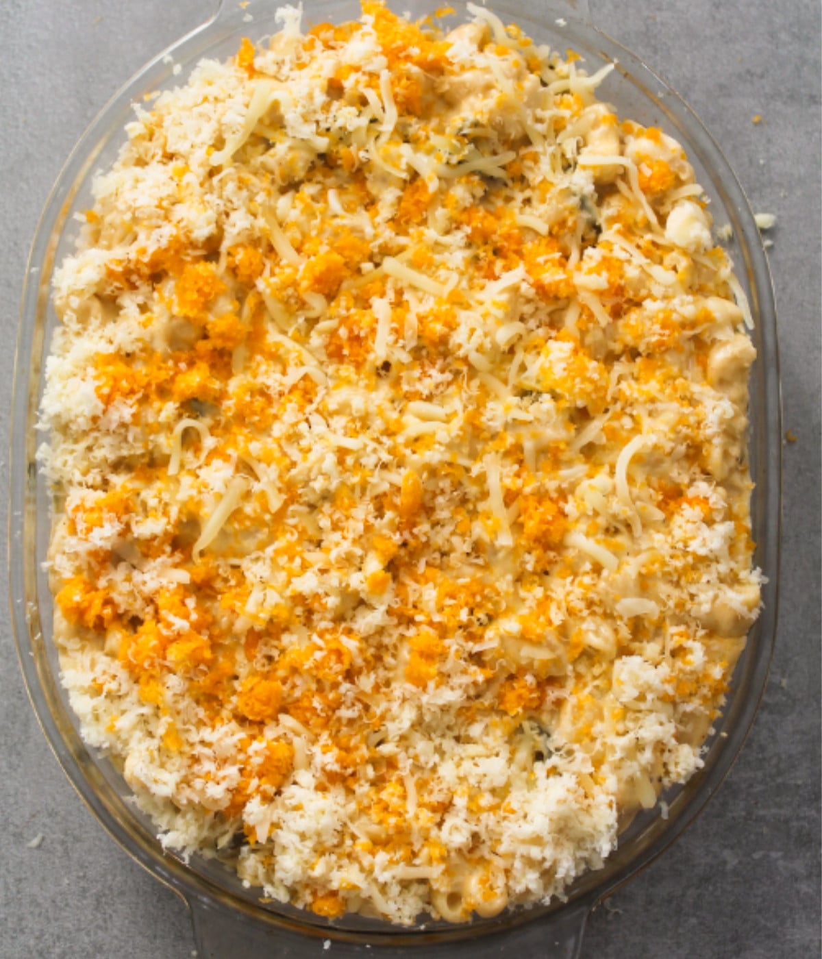 Jalapeno macaroni in a cheesy sauce topped with grated cheese in an oval oven dish.