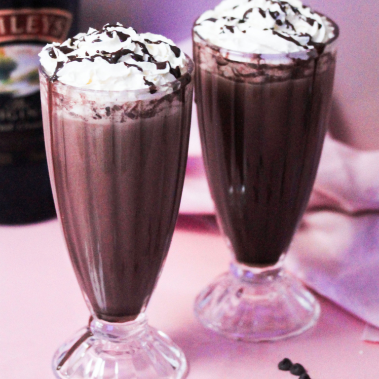 Baileys chocolate drink in two cups topped with whipped cream and chocolate sauce.