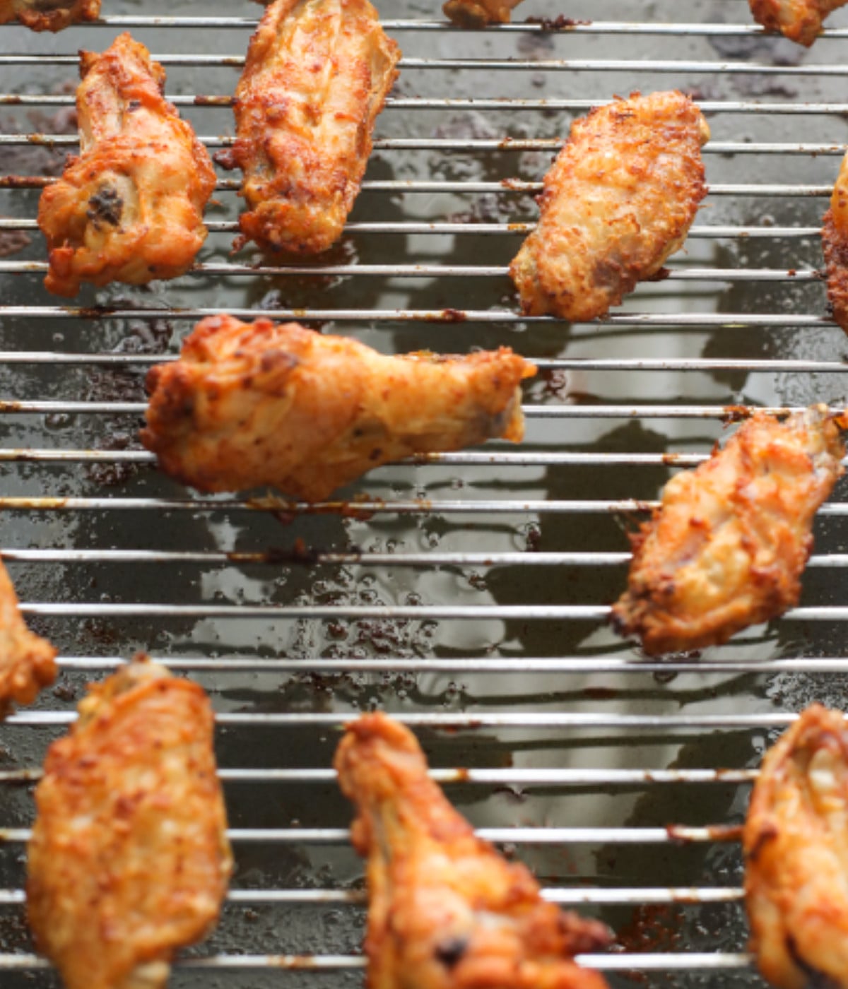 Baked crispy chicken wings on an oven rack.