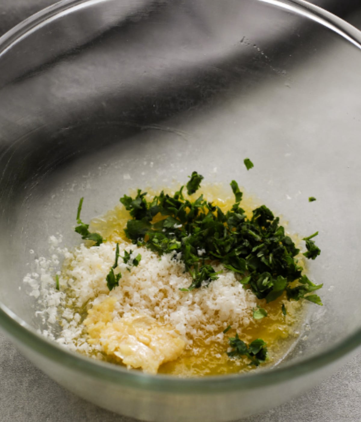 Melted butter, grated garlic, grated parmesan and parsley in a bowl.