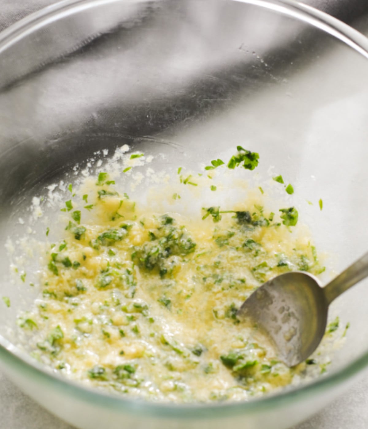 Melted butter, grated garlic, grated parmesan and parsley mixed in a bowl.