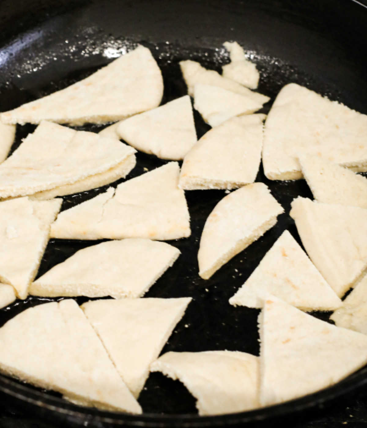 Chopped pita bread cooking in a black pan.