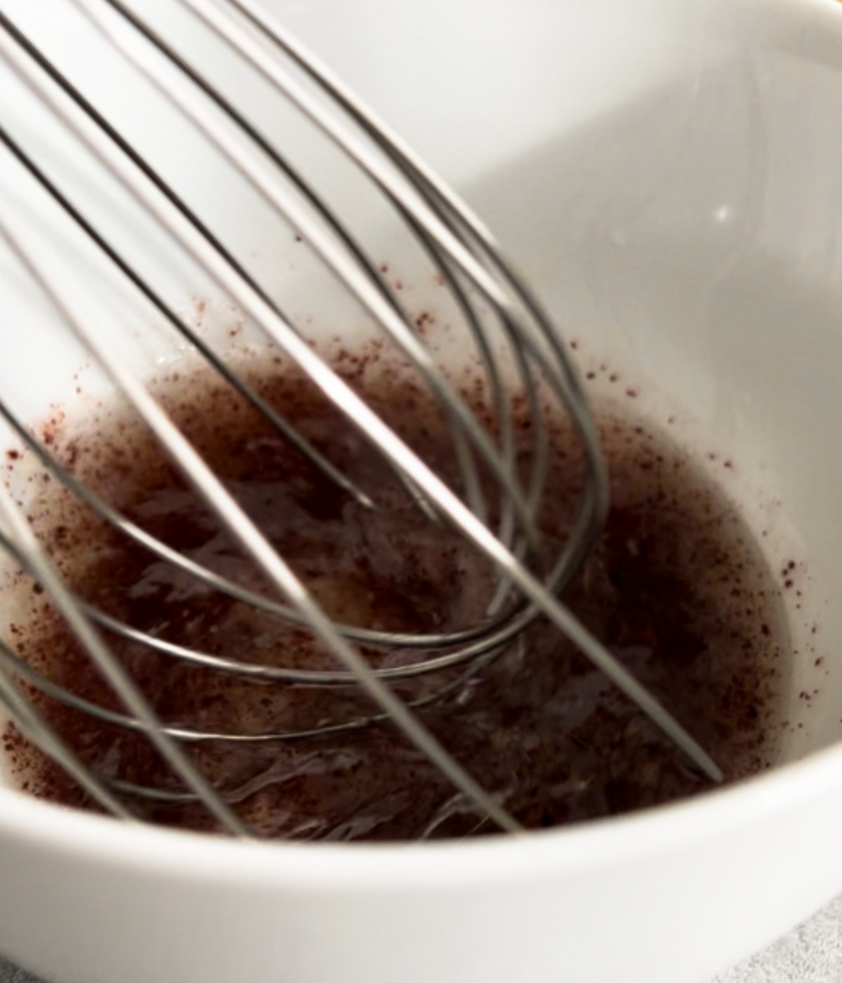 Oil, garlic, sumac and lemon juice whisked in a white bowl.