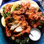 chicken dönmek kebab on a plate with salad, pita, dip with lemon.