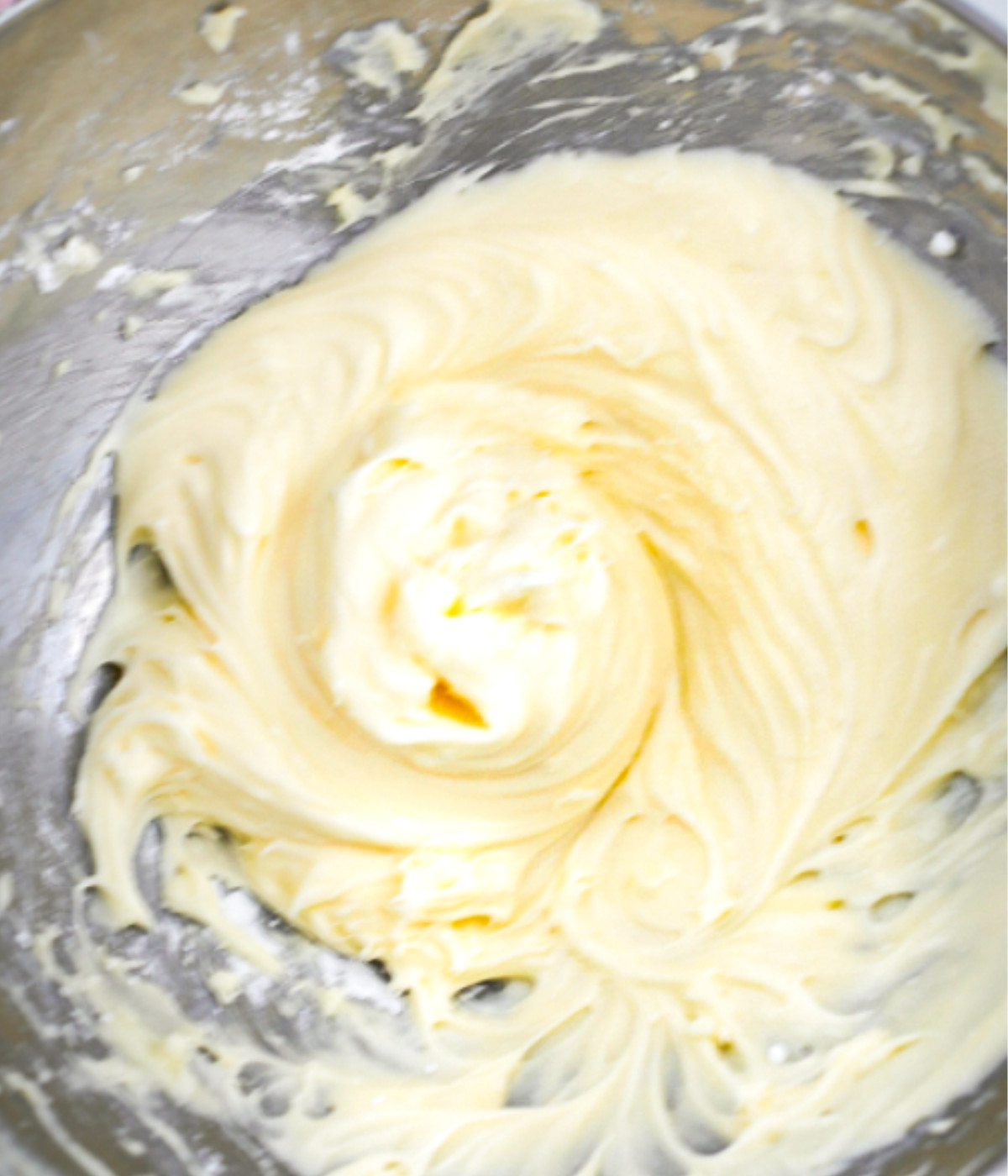 Whisked butter, cream cheese and icing sugar in a silver bowl.