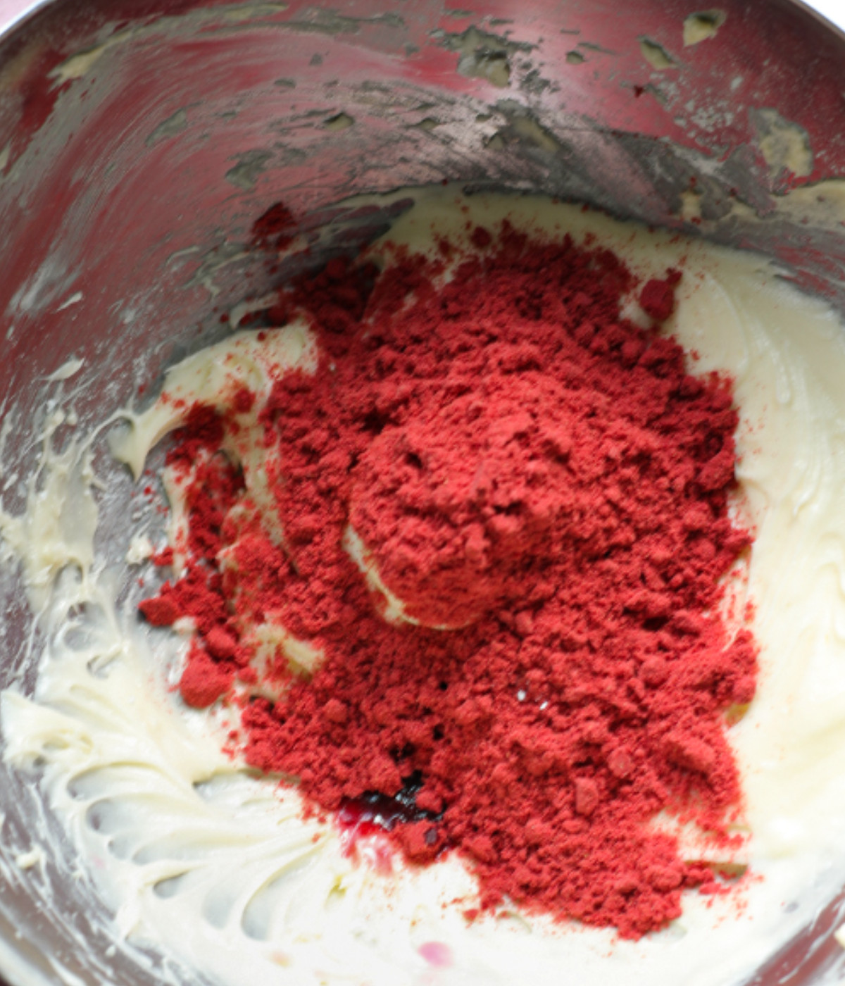 Whisked butter, cream cheese, freeze dried strawberries and icing sugar in a silver bowl.