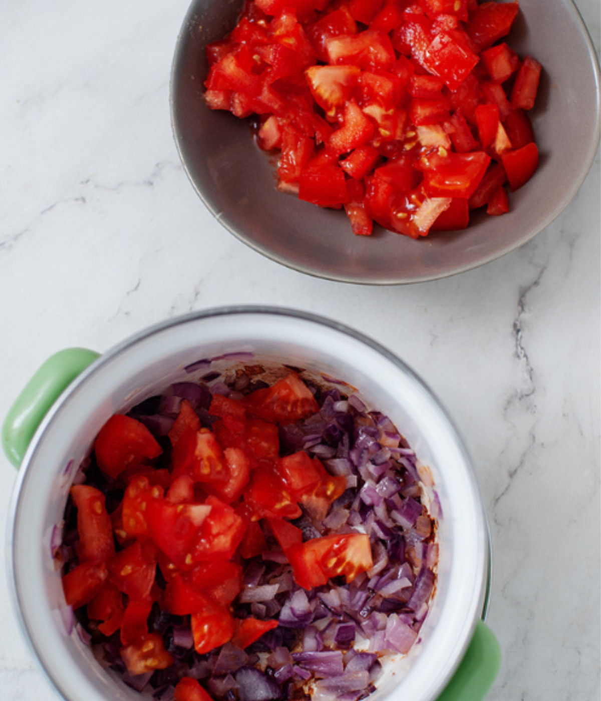 Chopped red onions and tomatoes in a white pot.