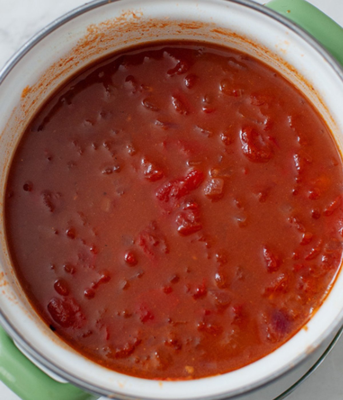 Chopped tomatoes, balsamic vinegar, brown sugar, ccooked in a white pot.