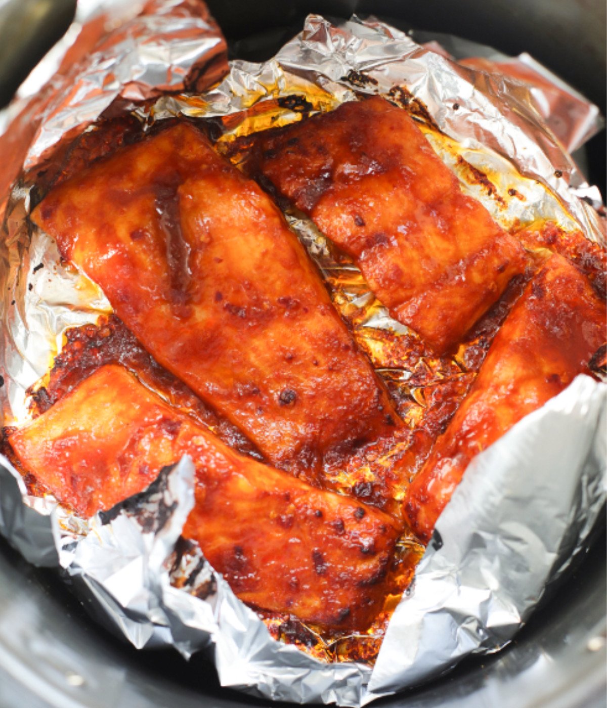 Air fried spicy salmon pieces in a lined air fryer.