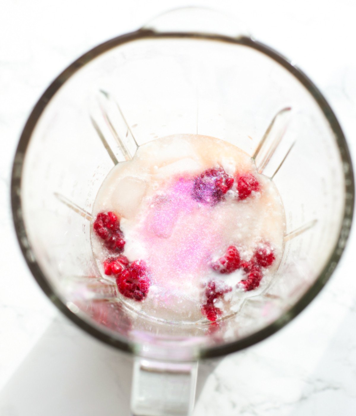 Frozen raspberries, coconut cream, ice and pink glitter in a mixer.