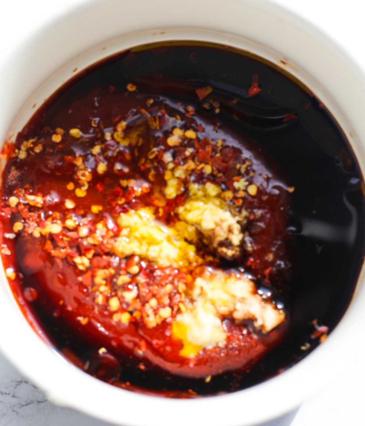 Soy sauce, garlic, chilli flakes, honey and sirracha in a bowl.