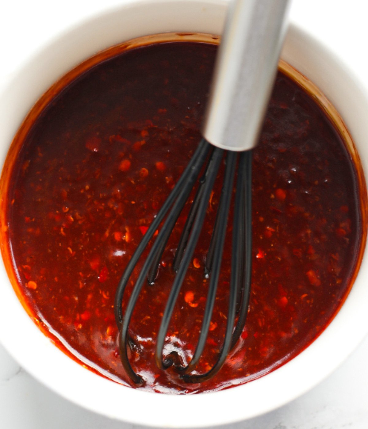 Soy sauce, garlic, chilli flakes, honey and sirracha whisked in a bowl.